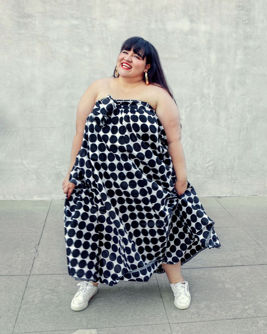 image of Mari wearing long polkadot dress with gold hoop earrings and a bright smile